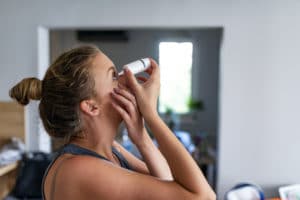 Photo of a woman using allergy drops. Female droppings Sublingual allergy drops to treat her allergies. 