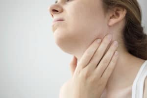 Young woman feeling painful in the throat. The young woman is rubbing her throat. 