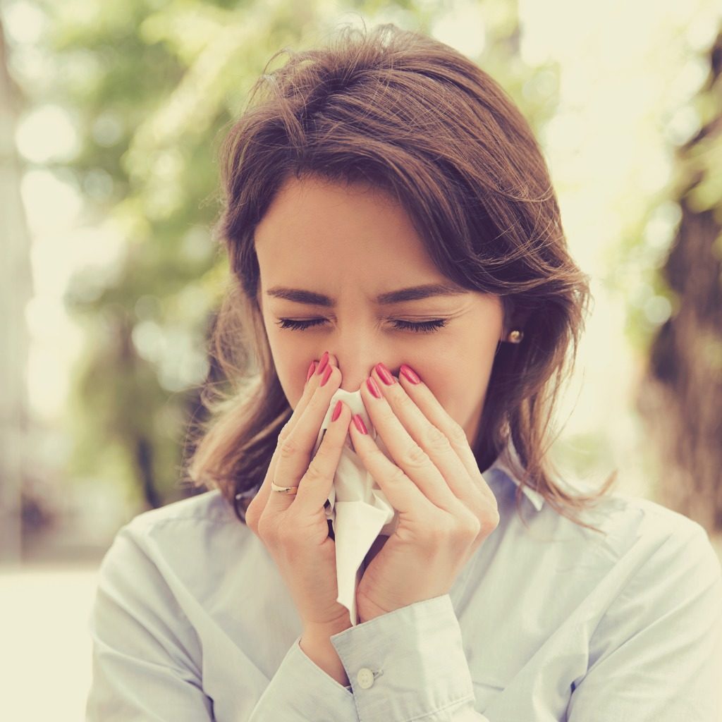 Woman with nonallergic rhinitis symptoms blowing nose stock photo