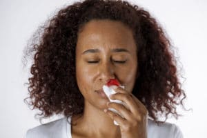 Woman using a sterile gauze bandage to stop a nosebleed.