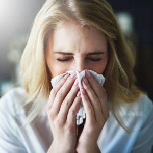 sick woman sneezing at home