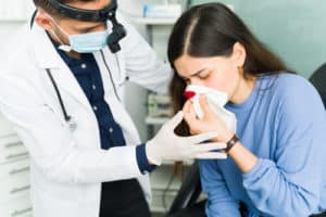 otolaryngologist trying to stop a nasal hemorrhage of a female patient