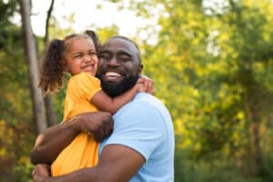 Dad and daughter outside hugging and enjoying the fresh air